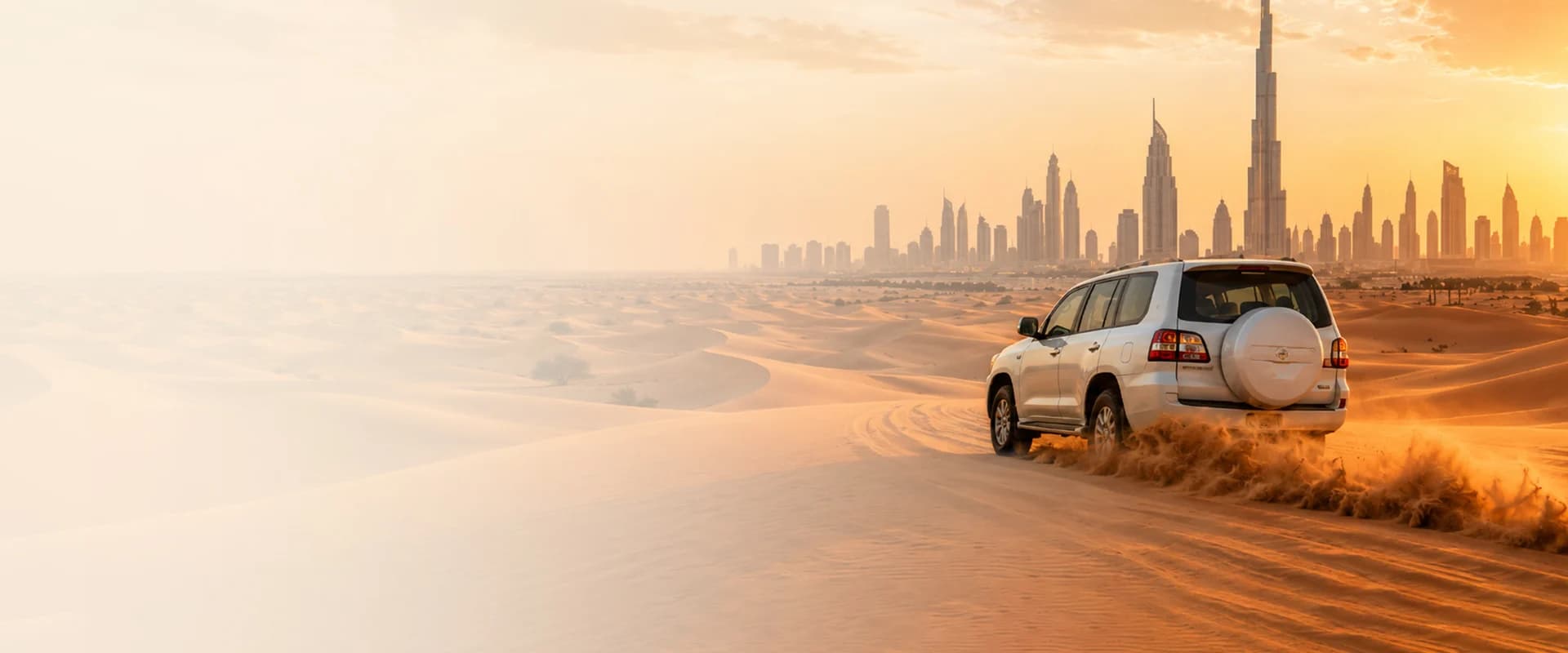 4x4 safari vehicle driving over desert dunes with the Dubai skyline behind at sunset